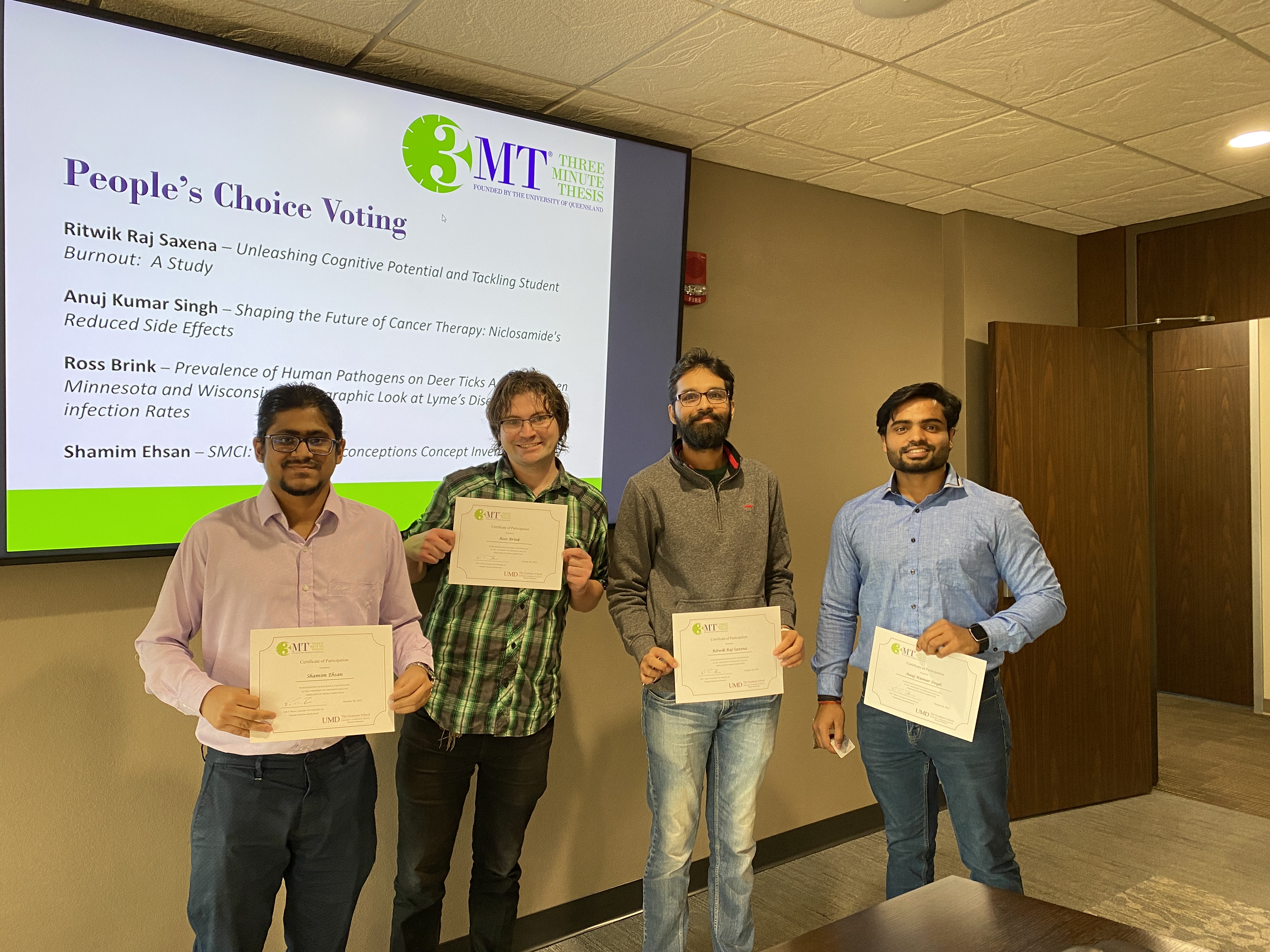 Four 3MT competitors holding participation certificates.